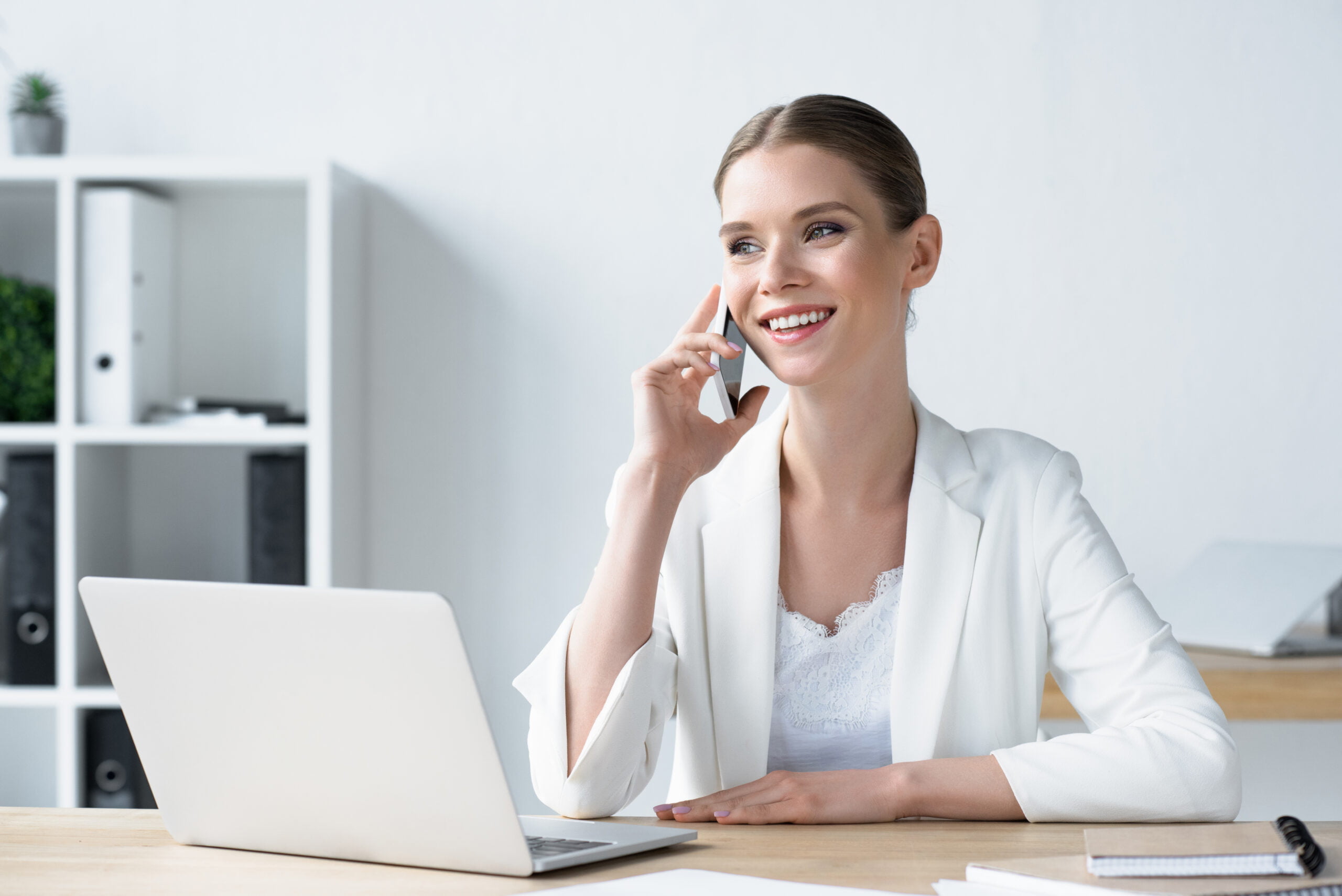 Business Woman Talking on Phone with laptop open on her desk