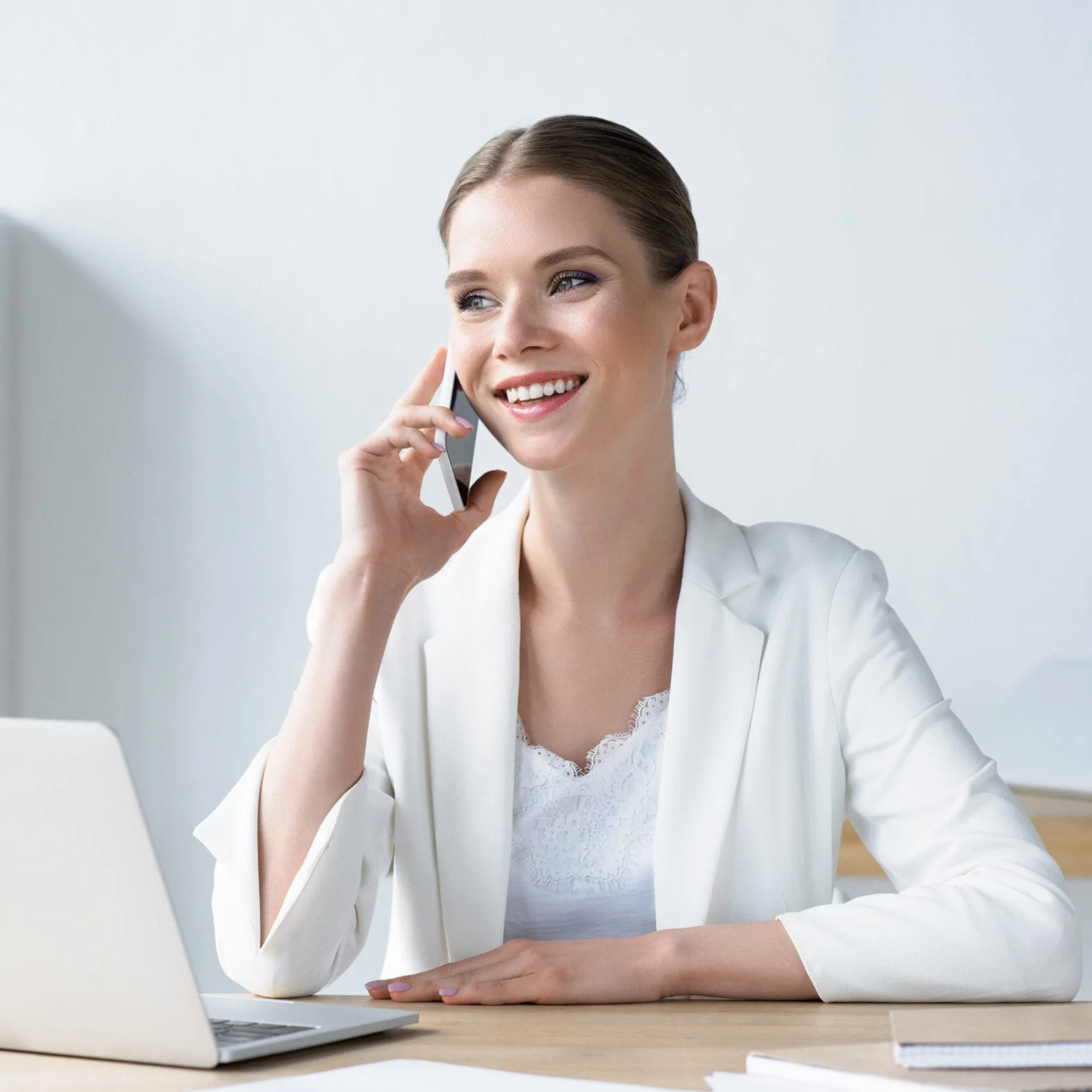 Business Woman Talking on Phone with laptop open on her desk